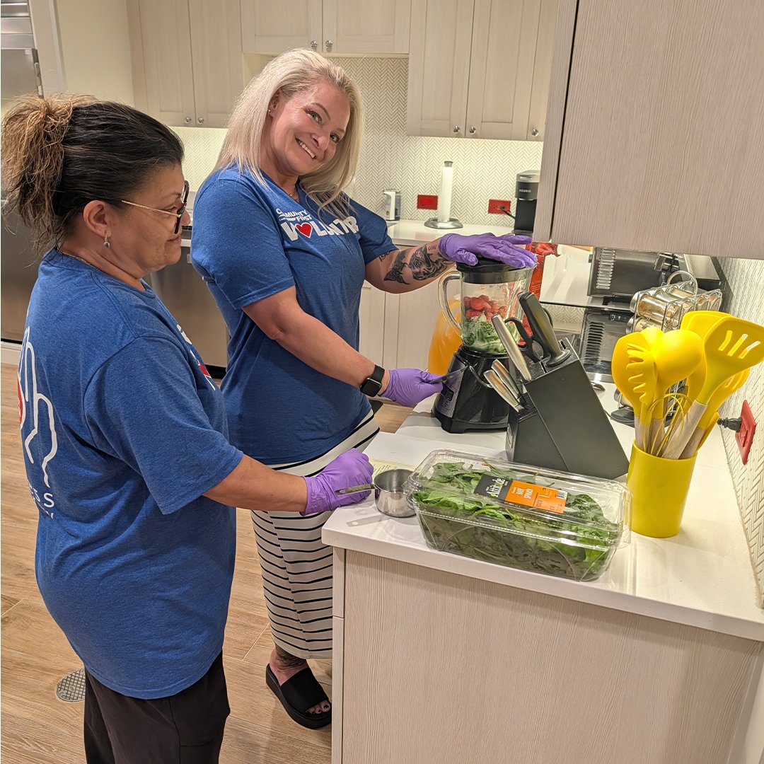 Volunteer smiling while making smoothie.