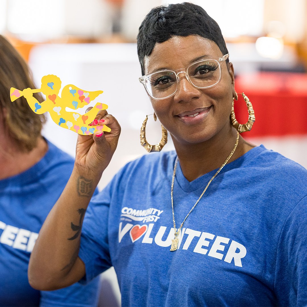 Volunteer smiling holding up craft.
