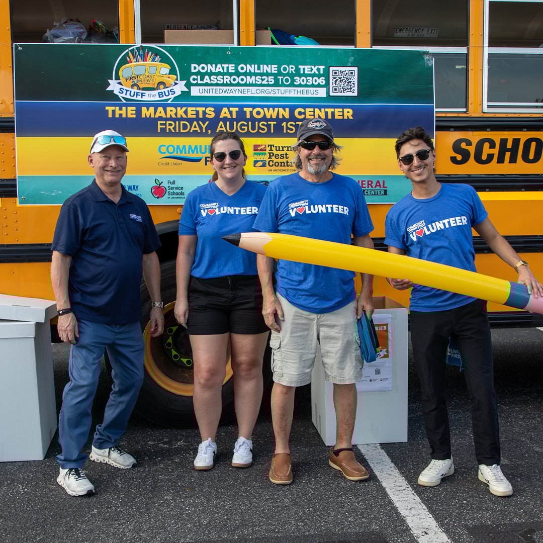 Volunteers holding a giant pencil at Stuff the Bus.