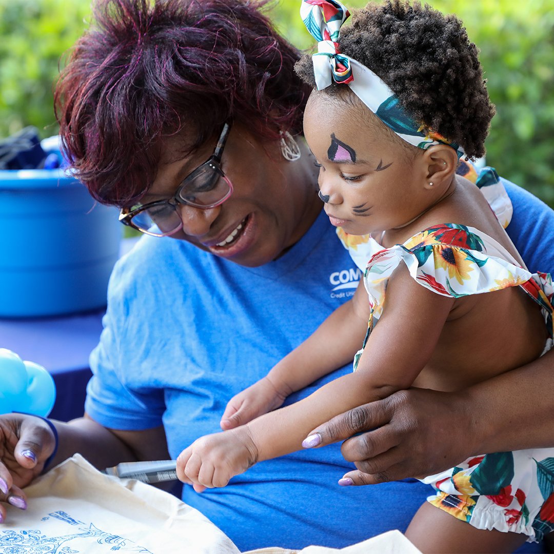 Volunteer holding child and coloring.
