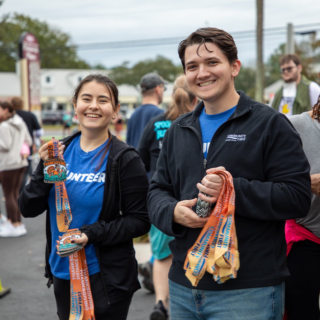 Volunteers smiling holding medals to give out at Kilwins Ice Cream Run.