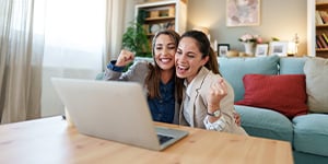 Two women cheering at laptop. Two women cheering at laptop.