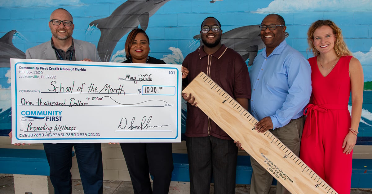 Teachers with big check and oversized ruler.