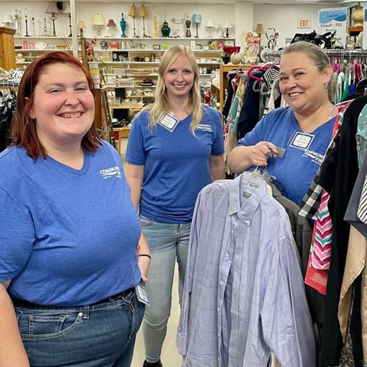 Volunteers at Barnabas holding clothes.