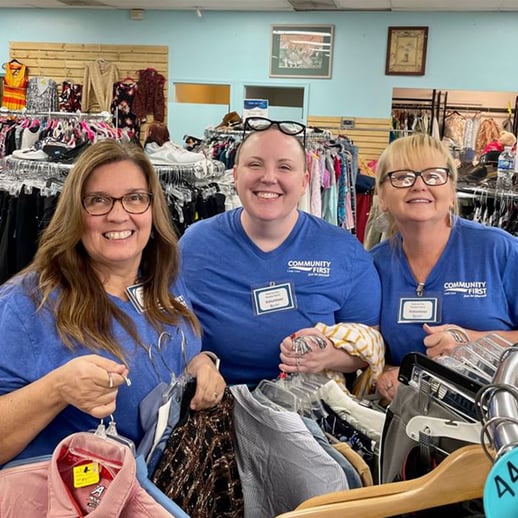 Volunteers at Barnabas holding clothes.