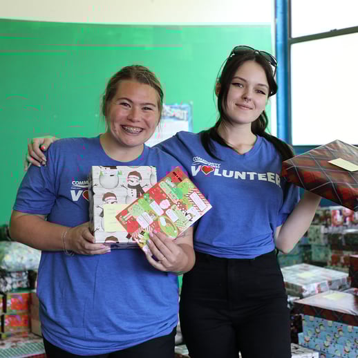 Volunteers smiling holding presents.