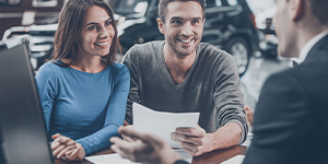 happy-couple-at-a-car-dealership-reviewing-finance-options